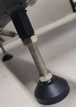 Load image into Gallery viewer, A picture of the foot pad/weld nut mounted underneath a workbench
